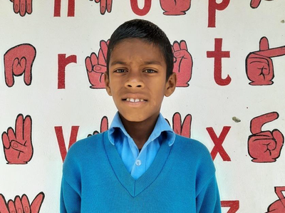 Ein Schüler aus dem Gehörlosenzentrum Siraha vor einer Wand mit Gebärden Zeichnungen