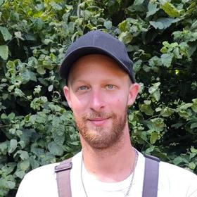 Friedholfsküster Kevin Köhler steht vor einer grünen Hecke 