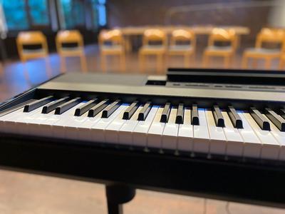 Tasten des E-Pianos im Vordergrund und Stuhlkreis im Hindergrund